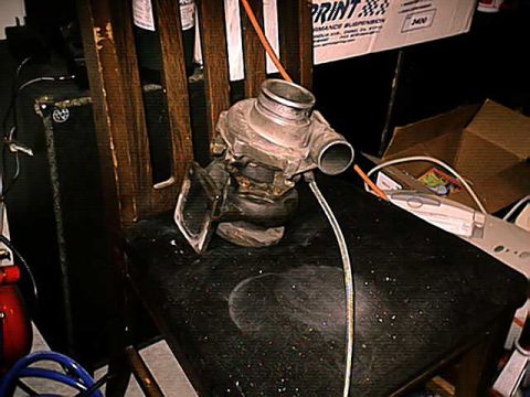 1994 Ford Probe - A turbocharger sits on a chair in a cluttered garage setting.