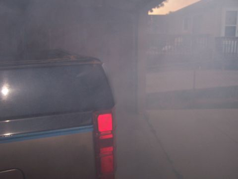 1986 Ford Bronco - Thick smoke billows from the rear of an SUV, obscuring the view of the surrounding area.