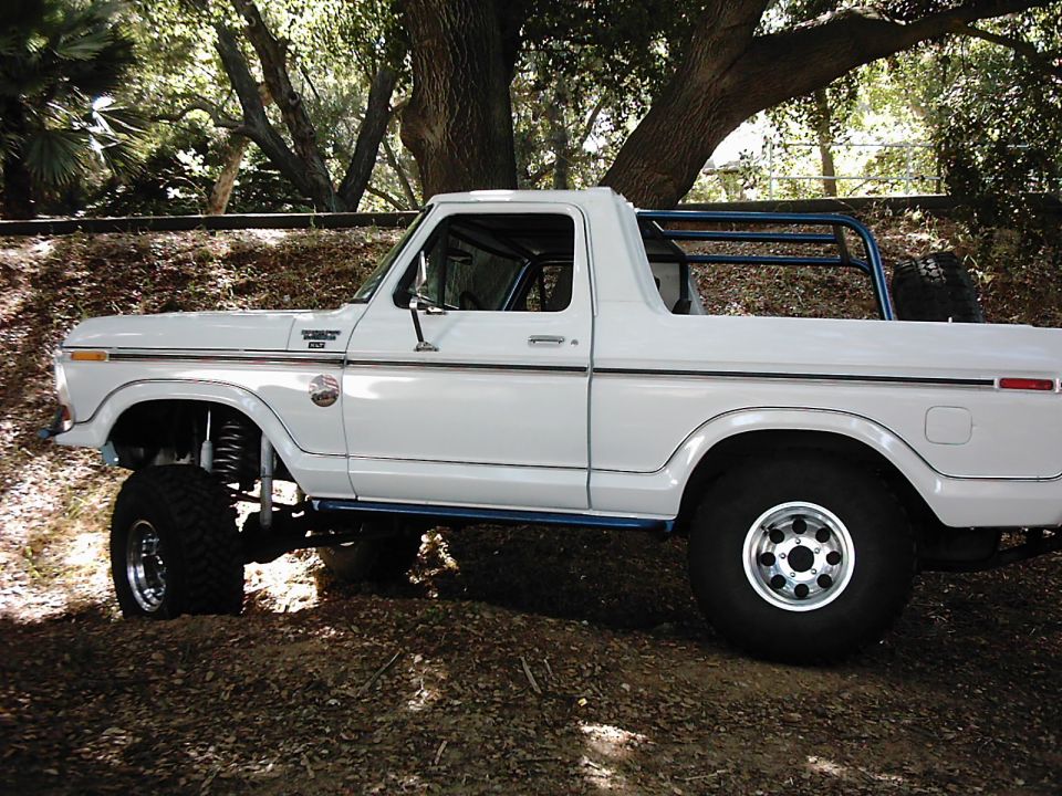 White 1978 Ford Bronco lifted with roll cage, parked outdoors
