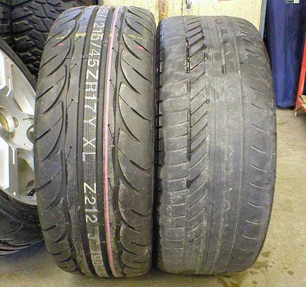 Two 215/45ZR17 performance tires side by side on shop floor, one worn