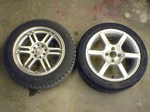 2004 Ford Focus - Two aftermarket wheels and tires are shown on a concrete surface.