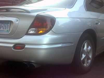 2002 Oldsmobile Aurora - Rear view of a silver sedan with a spoiler and dual exhaust pipes.