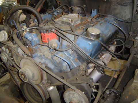 1979 Ford Bronco - Grimy Ford V8 sitting in the engine bay with the air cleaner and carburetor removed to expose the intake manifold opening, showing blue val…