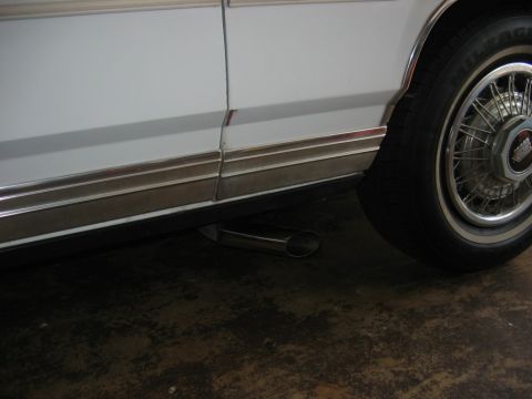 1985 Ford LTD Crown Victoria - A close-up view of a car's chrome exhaust tip and wheel.