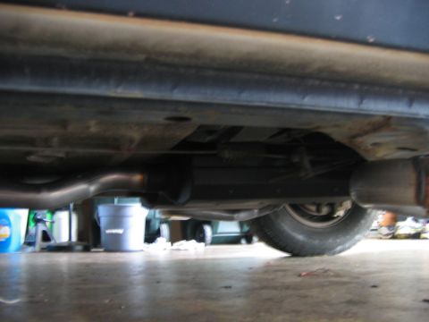 1985 Ford LTD Crown Victoria - Close-up of a car's undercarriage, focusing on the exhaust system and a rear tire.