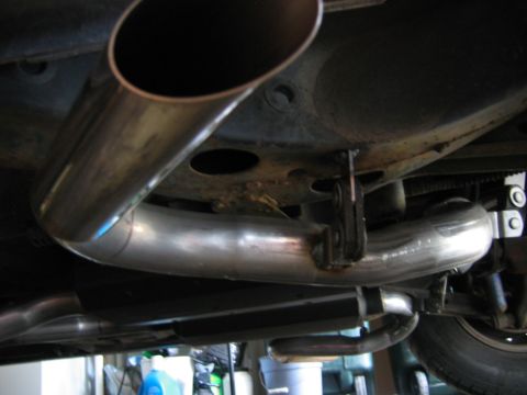 1985 Ford LTD Crown Victoria - Underside view of a vehicle's exhaust system, highlighting the metal piping and mounting hardware.