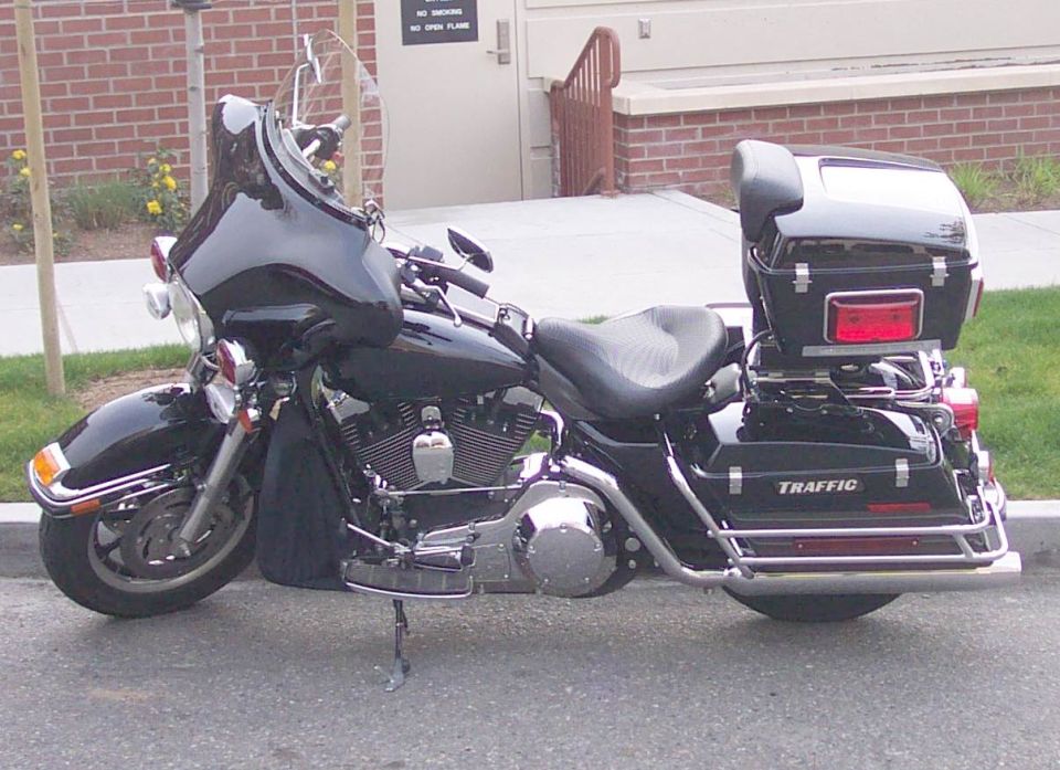 Black Harley touring motorcycle, side view, with fairing, top case, and TRAFFIC saddlebag