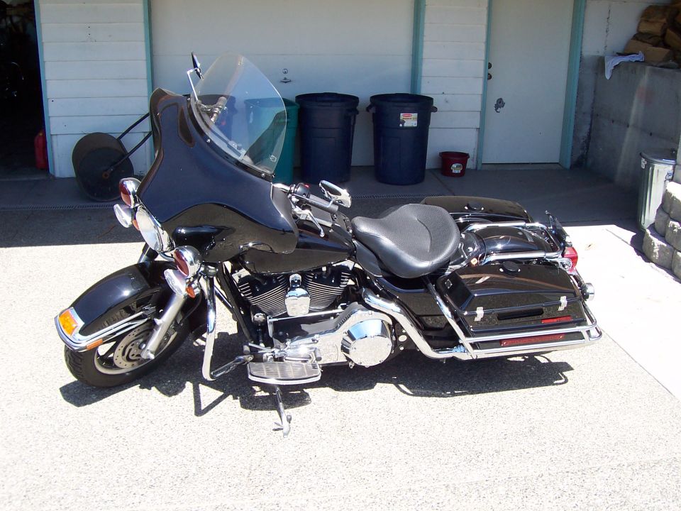 Black Harley bagger with batwing fairing and windshield parked outside a garage