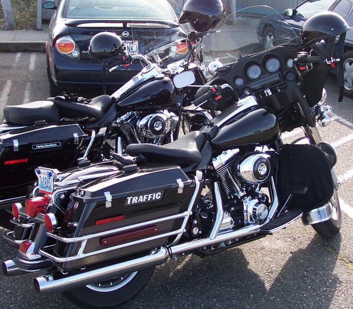 Two black Harley touring motorcycles parked side by side, one with TRACTION saddlebag lettering