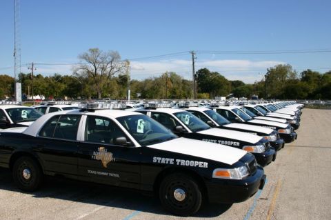 2000 Ford Crown Victoria - A line of Texas Highway Patrol Ford Crown Victoria police cruisers are parked in a lot under a clear blue sky.