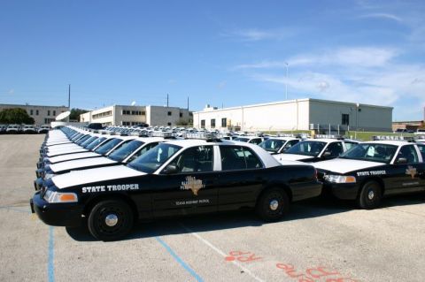 2000 Ford Crown Victoria - Multiple Texas Highway Patrol Ford Crown Victoria police cars are lined up in a parking lot under a clear blue sky.