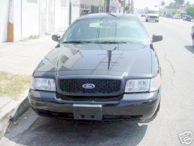 2003 Ford Crown Victoria - A black 2003 Ford Crown Victoria is parked on the side of a street.
