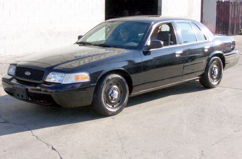 2003 Ford Crown Victoria - A black 2003 Ford Crown Victoria sedan is parked outside on a sunny day.