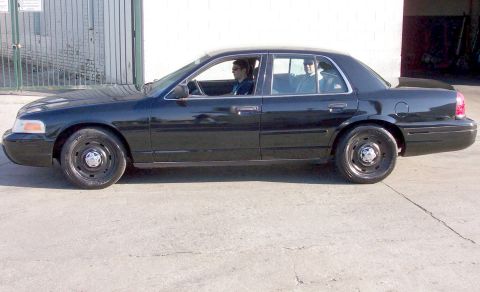 2003 Ford Crown Victoria - Side profile of a black 2003 Ford Crown Victoria sedan with two occupants.