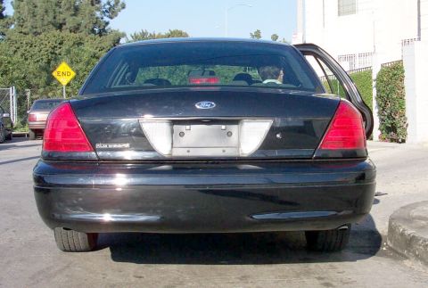 2003 Ford Crown Victoria - The rear of a black 2003 Ford Crown Victoria is shown with the driver's side door ajar.