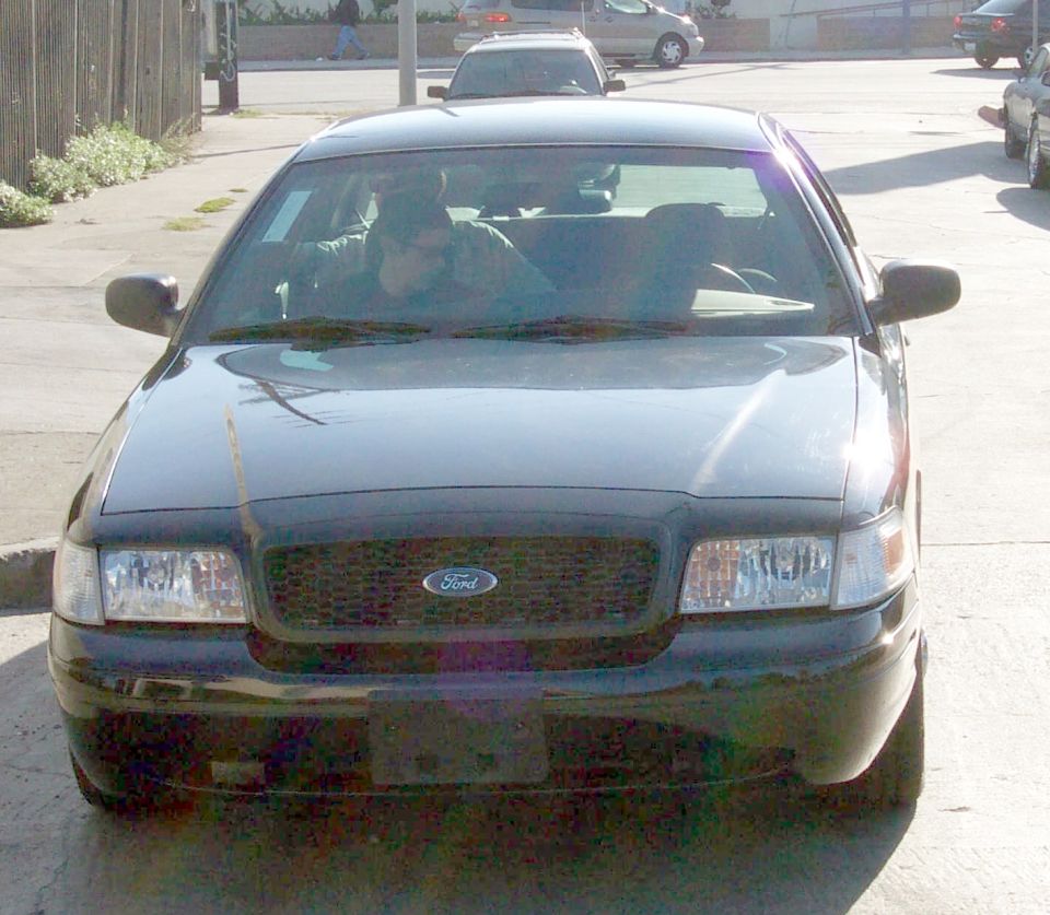 Black 2003 Ford Crown Victoria, front view, parked on street, two people inside