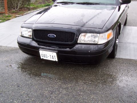 2003 Ford Crown Victoria - Front view of a black 2003 Ford Crown Victoria, showing the grille and headlights.