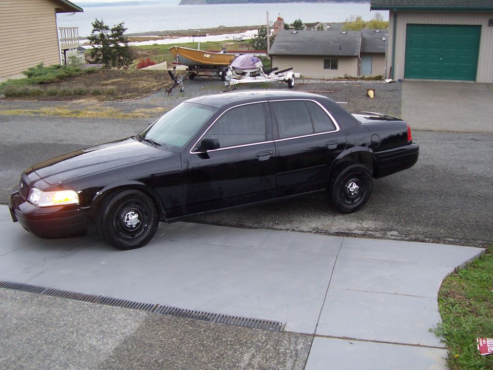 2003 Ford Crown Victoria parked on driveway with a boat and trailer in the background