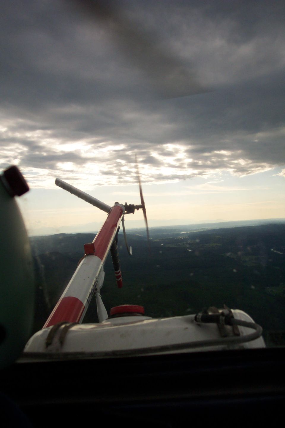 View from inside a helicopter looking out at the rotor and landscape below