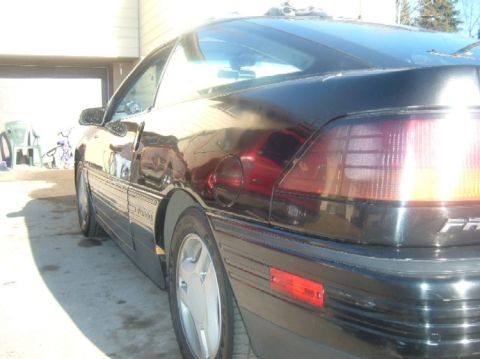 1989 Ford Probe - The rear passenger side of a black coupe is visible, parked in a driveway.