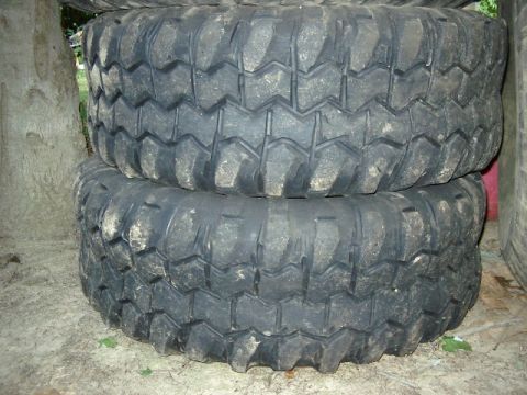 1985 Ford Bronco - A close-up view shows two large, knobby off-road tires stacked outdoors.