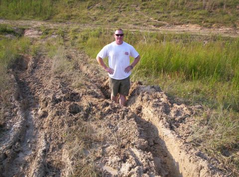 1995 Ford Bronco - Man stuck in mud with tire tracks, off-road scene.