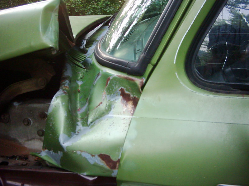 Green 1974 Ford F-250 fender and door showing significant collision damage