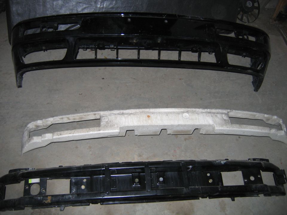 Three car bumpers stacked, one black, one white foam, one black metal
