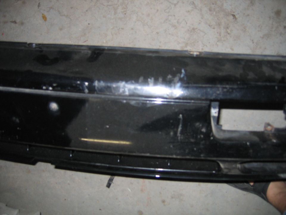 black car bumper with scuffs and a rectangular cutout