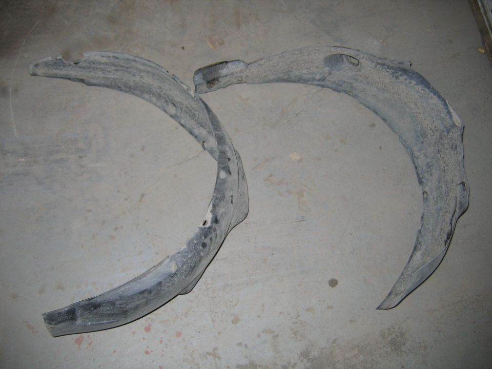 Two used plastic fender liners on a concrete floor