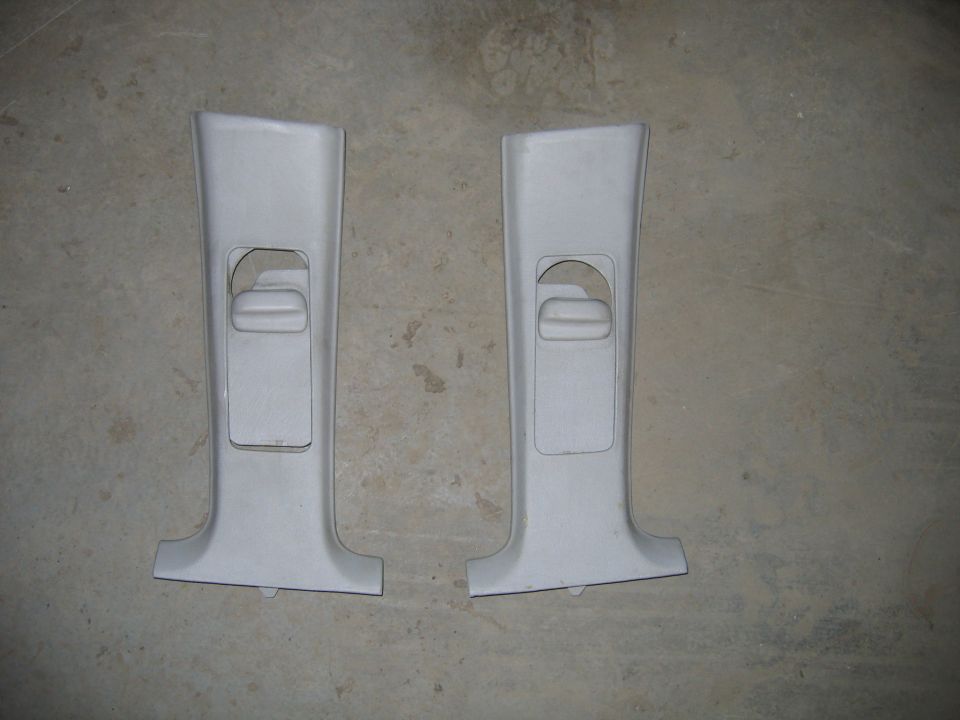 Two light gray plastic interior trim pieces with cutouts for controls, laid on a concrete floor