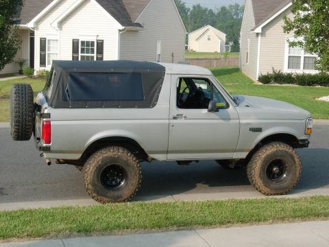 1995 Ford Bronco - Side view of a 1995 Ford Bronco a soft top and external spare tire mount.