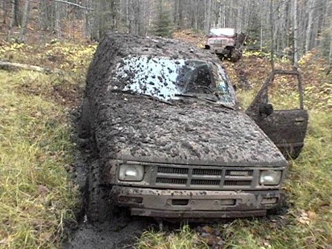 1995 Ford Bronco - Muddy 1995 Ford Bronco stuck off-road, with another vehicle visible in the background.