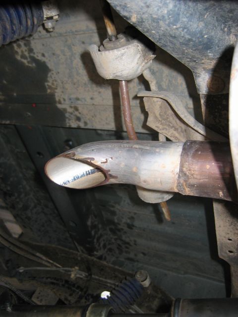 1995 Ford Bronco - Underside view of a vehicle's exhaust system, focusing on a worn exhaust hanger and pipe.