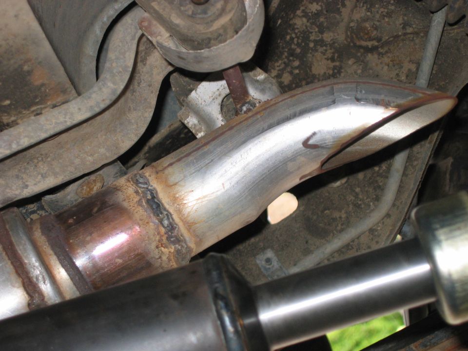 Close-up of an exhaust pipe with visible welds and suspension parts underneath a vehicle
