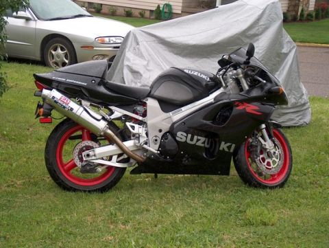 2002 Suzuki TL1000R - A black Suzuki sportbike with red wheels is parked on the grass next to a covered vehicle and a silver car.