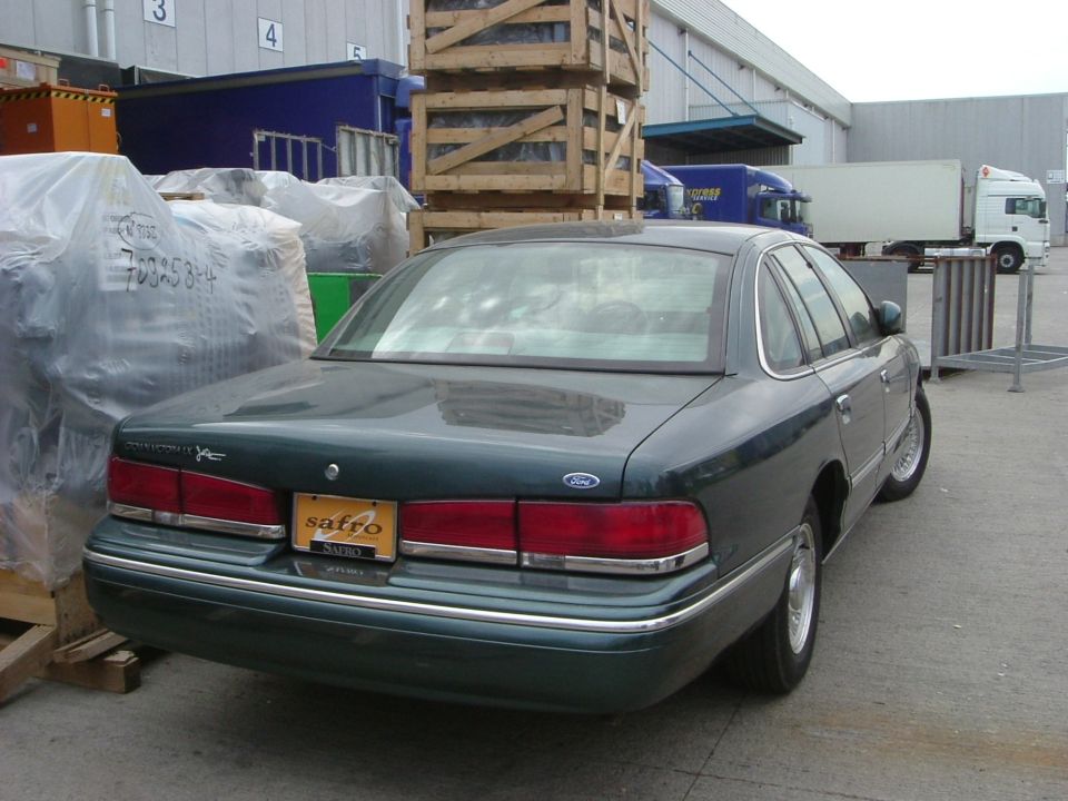 1996 Ford Crown Victoria sedan parked outdoors near industrial buildings, rear view
