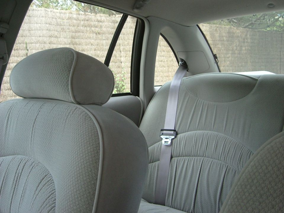 Car interior with light grey fabric seats and seatbelts. A watermark reads SUPERMOTORS