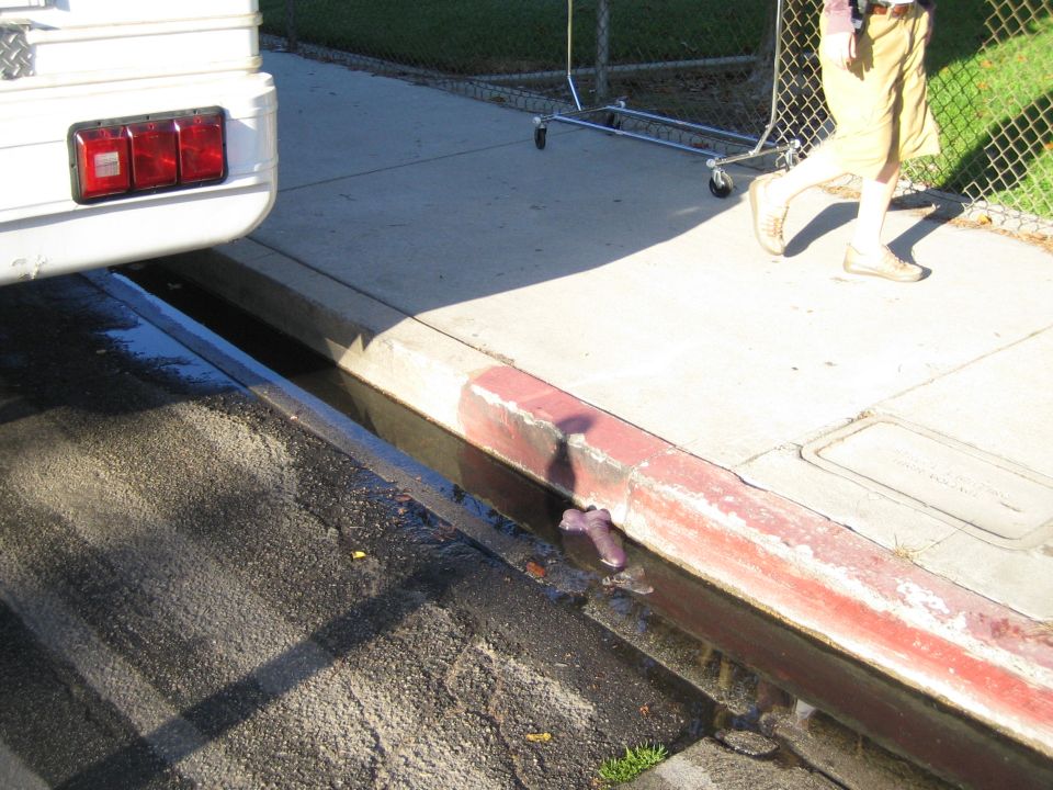 Truck tail end on a driveway above a sunken trench with a person standing nearby