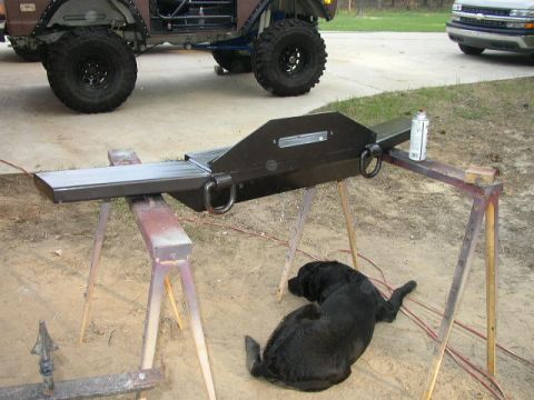 1995 Ford Bronco - A custom bumper is shown on sawhorses, with a black dog resting in the dirt and another vehicle visible in the background.