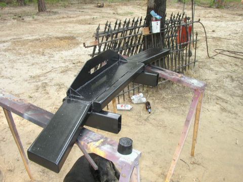 1995 Ford Bronco - A black metal bumper is being worked on outdoors, with spray paint cans and a fence in the background.