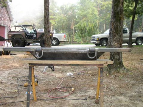 1995 Ford Bronco - Custom metal bumper with D-rings on sawhorses, with vehicles in the background.