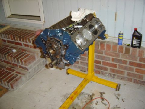 1986 Ford Bronco - Engine block on a stand, with parts and fluids on a brick ledge.
