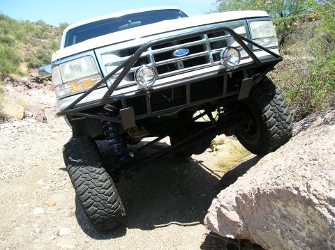 1993 Ford Bronco - This modified Ford truck navigates a rocky trail with its front tire elevated.