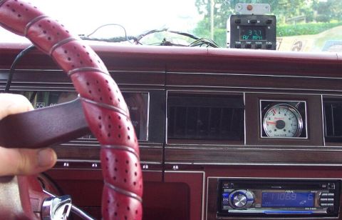 1985 Ford Crown Victoria LTD - Interior view of a car's dashboard showing a red-wrapped steering wheel and various gauges.