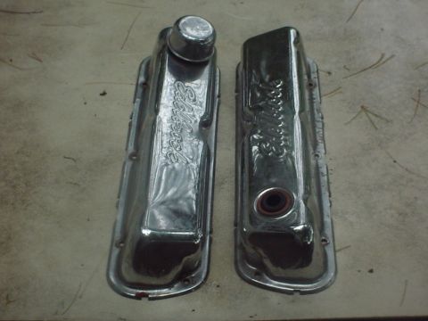 1979 Ford Bronco - Two chrome Edelbrock valve covers are shown, one with a red gasket, on a textured surface.