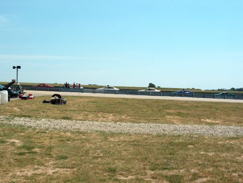1998 Ford Taurus - Cars are staged on a racetrack under a bright, clear sky.