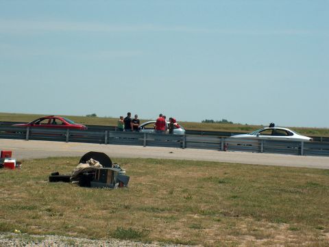 1998 Ford Taurus - Two cars are lined up on a racetrack with spectators watching from behind a guardrail.