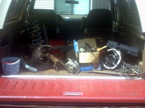 1989 Ford Bronco - Vehicle interior packed with various automotive parts, including a differential and suspension components.