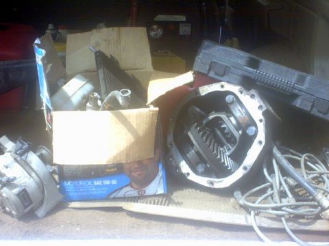 1989 Ford Bronco - Various car parts, including a differential and radiator, are piled in boxes.